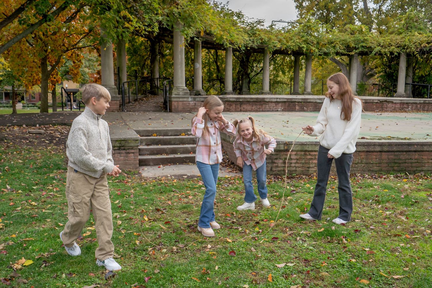 Children play and explore together in a park filled with autumn leaves on a crisp fall day.