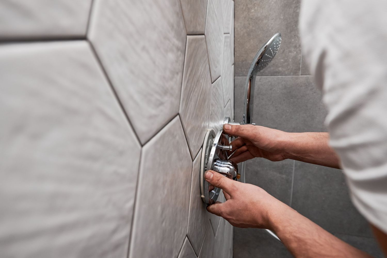 Hands using a sanding block to smooth out joint compound on a textured wall during drywall repair.