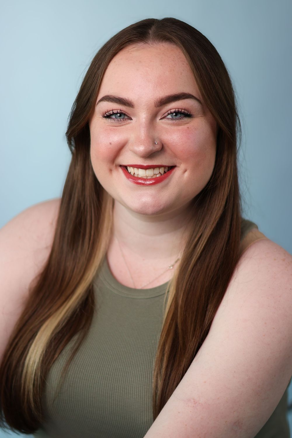 A series of headshots showing someone with long brown hair and bright smile wearing an olive green tank top against a blue background.