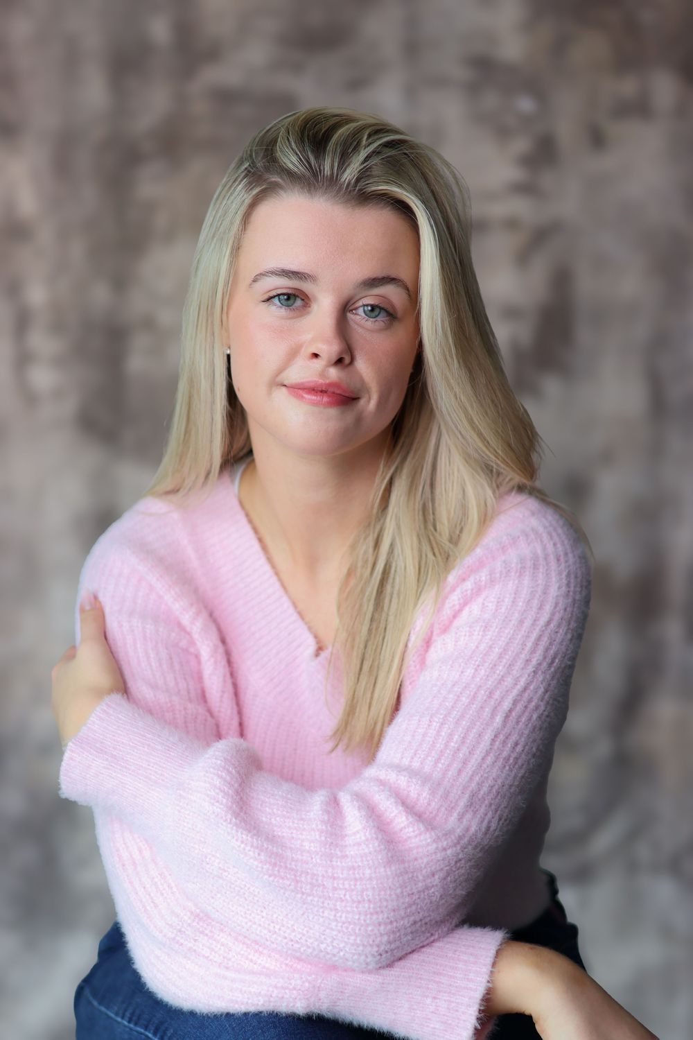 A series of photos showing someone wearing a soft pink knit cowl scarf against a textured gray background.