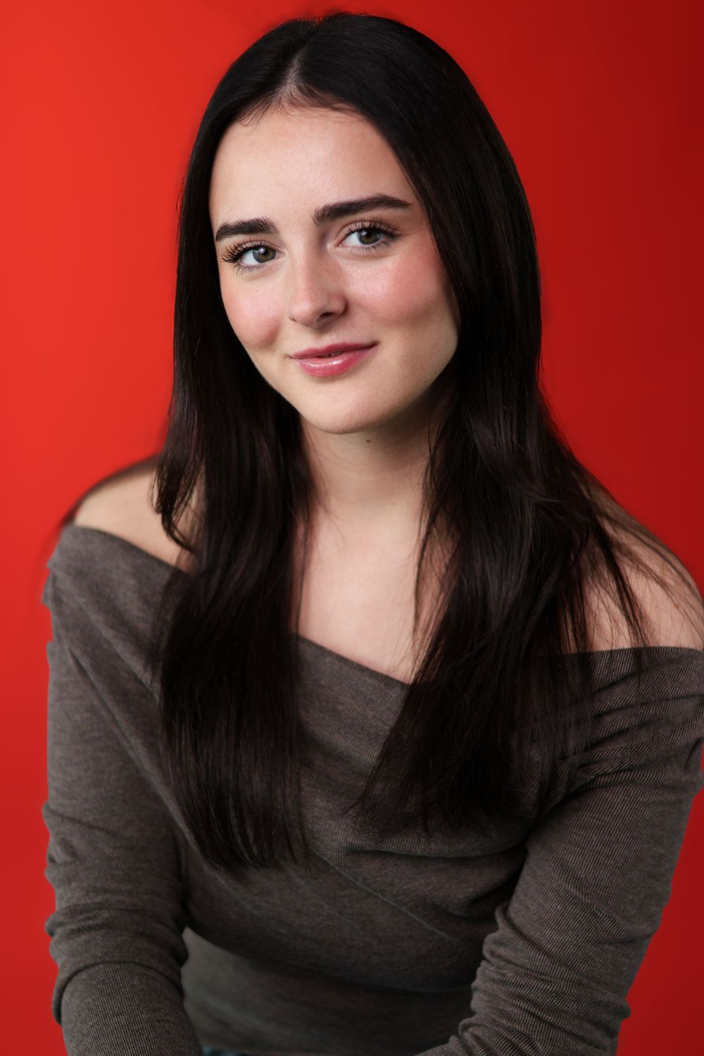 Portrait series against red background showing different poses of a person with long dark hair wearing a brown sweater.