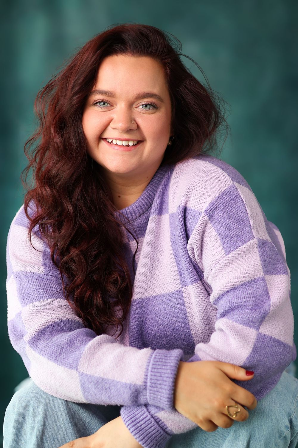 A series of photos showing someone wearing a cozy purple and white striped sweater against a teal background.