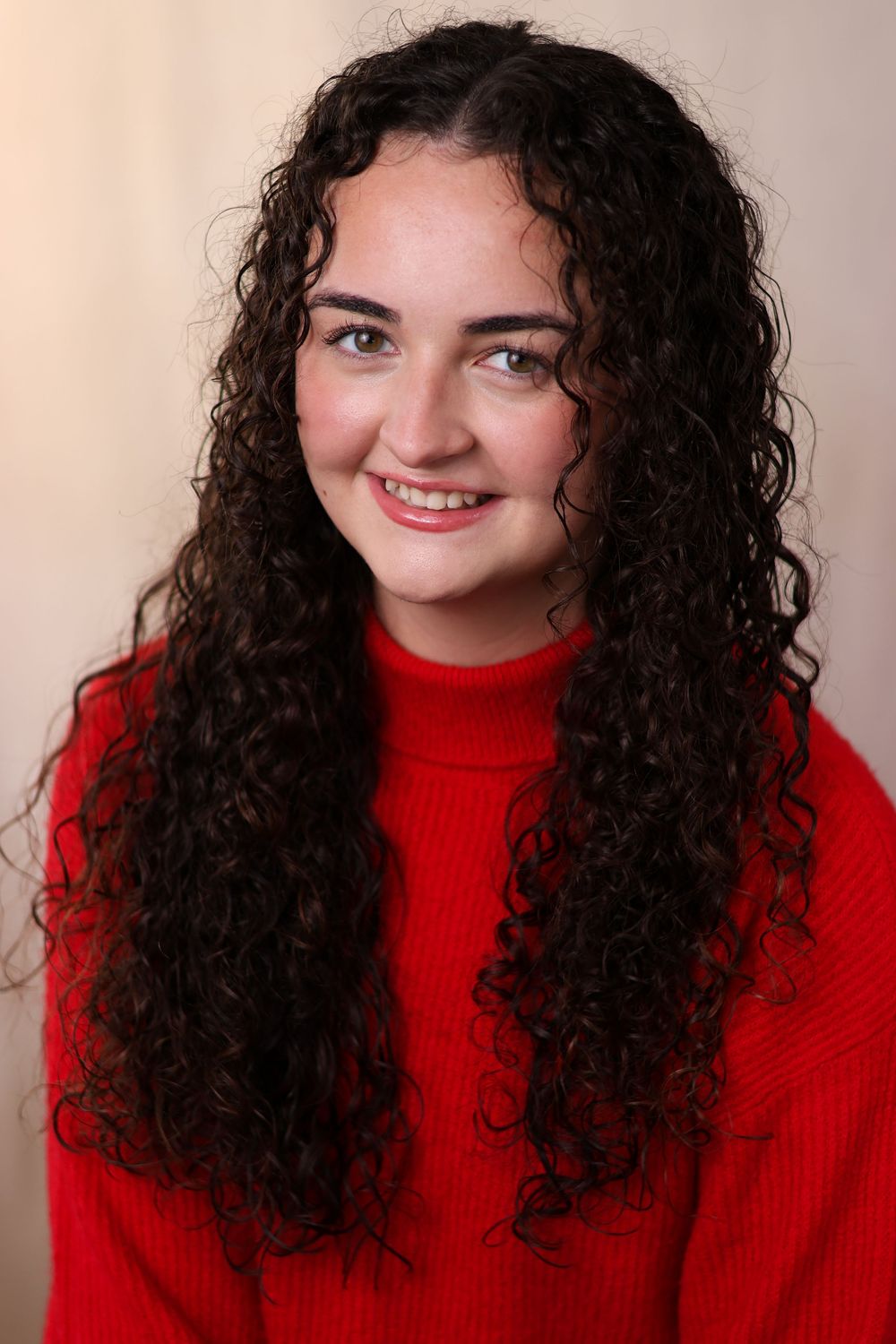 A series of five portraits showing someone with curly dark hair wearing a bright red turtleneck sweater against a neutral background.