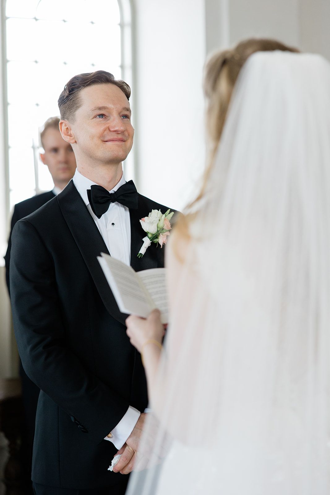 A first look moment between a bride and groom in formal wedding attire in a bright, elegant venue.
