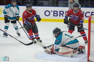 Hockey players scramble for the puck near the goal during an intense ice hockey match.