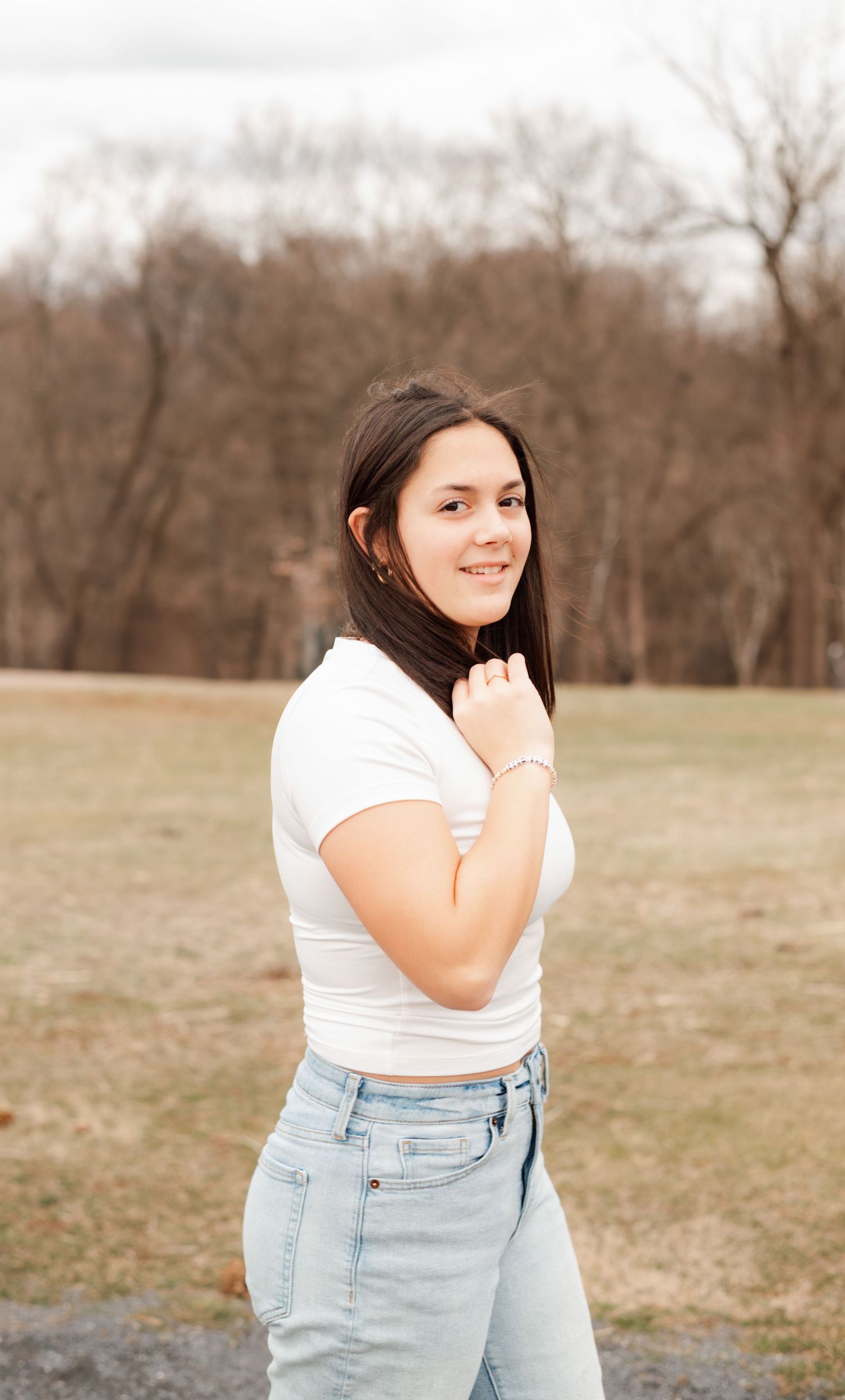 A series of outdoor photos showing someone wearing a black and gold varsity letterman jacket against a natural backdrop.