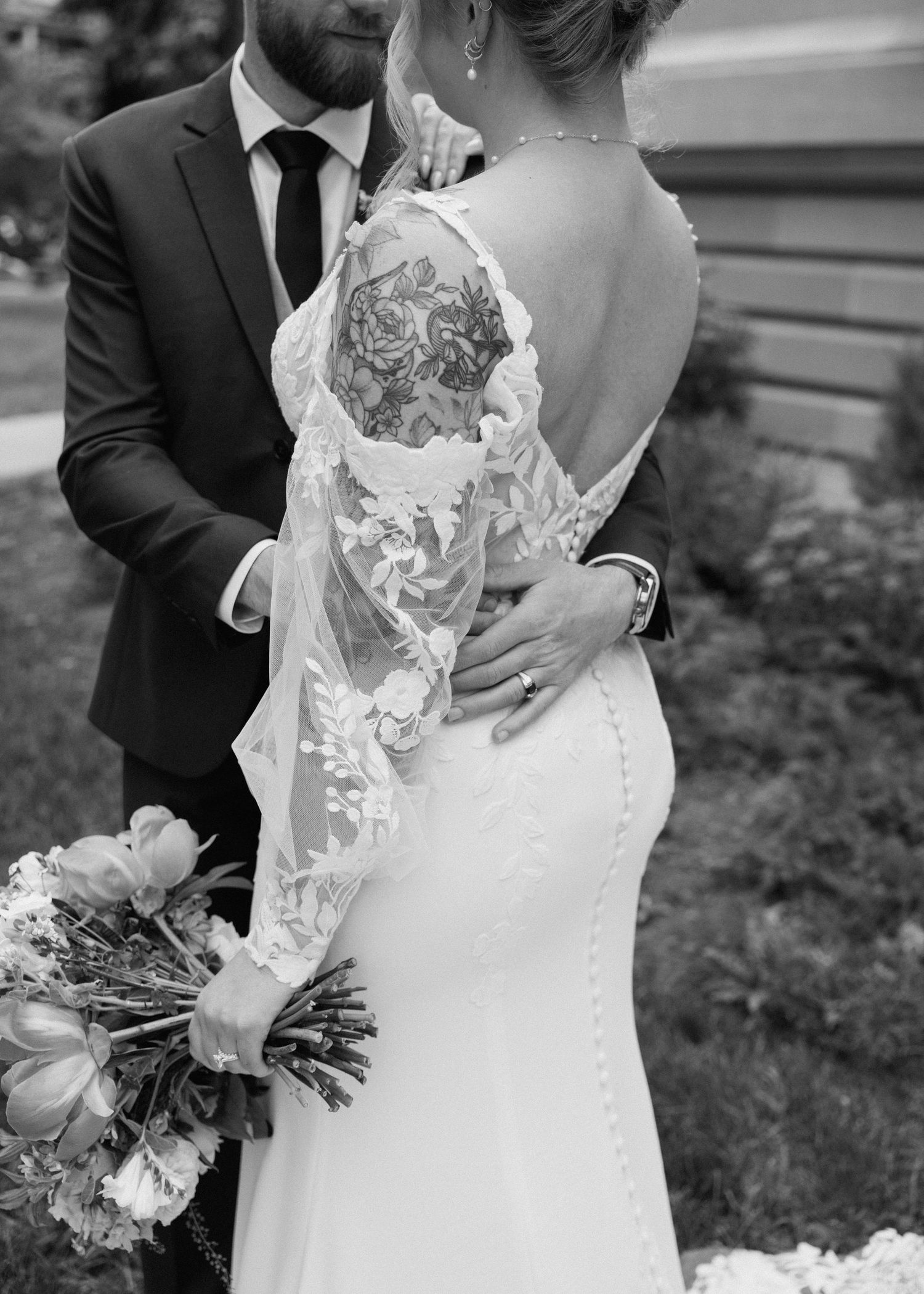 Elegant wedding dress details showing delicate lace and floral elements in black and white photography.