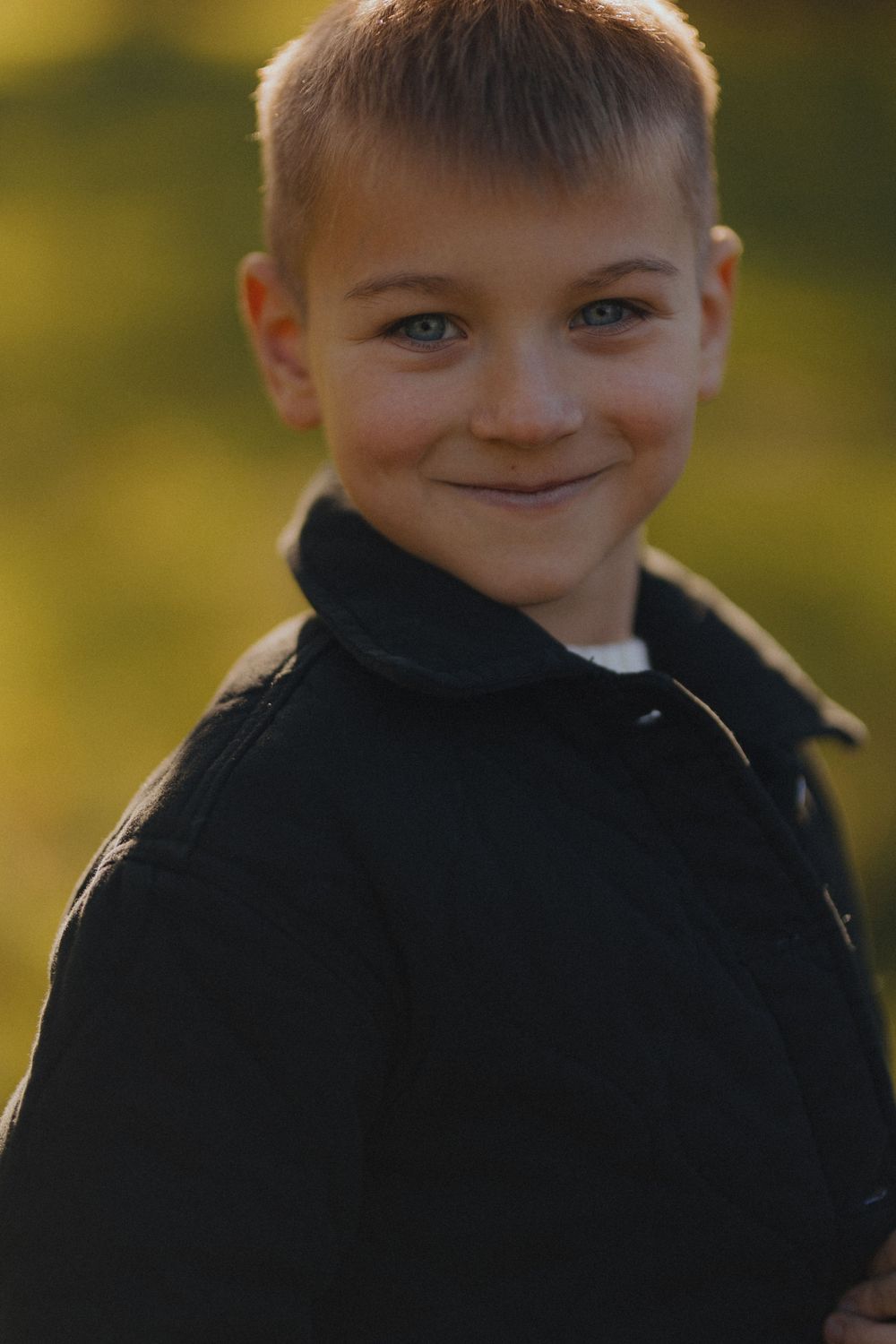 A sequence of five photos showing a child in a black hoodie making playful expressions against a blurred green background.