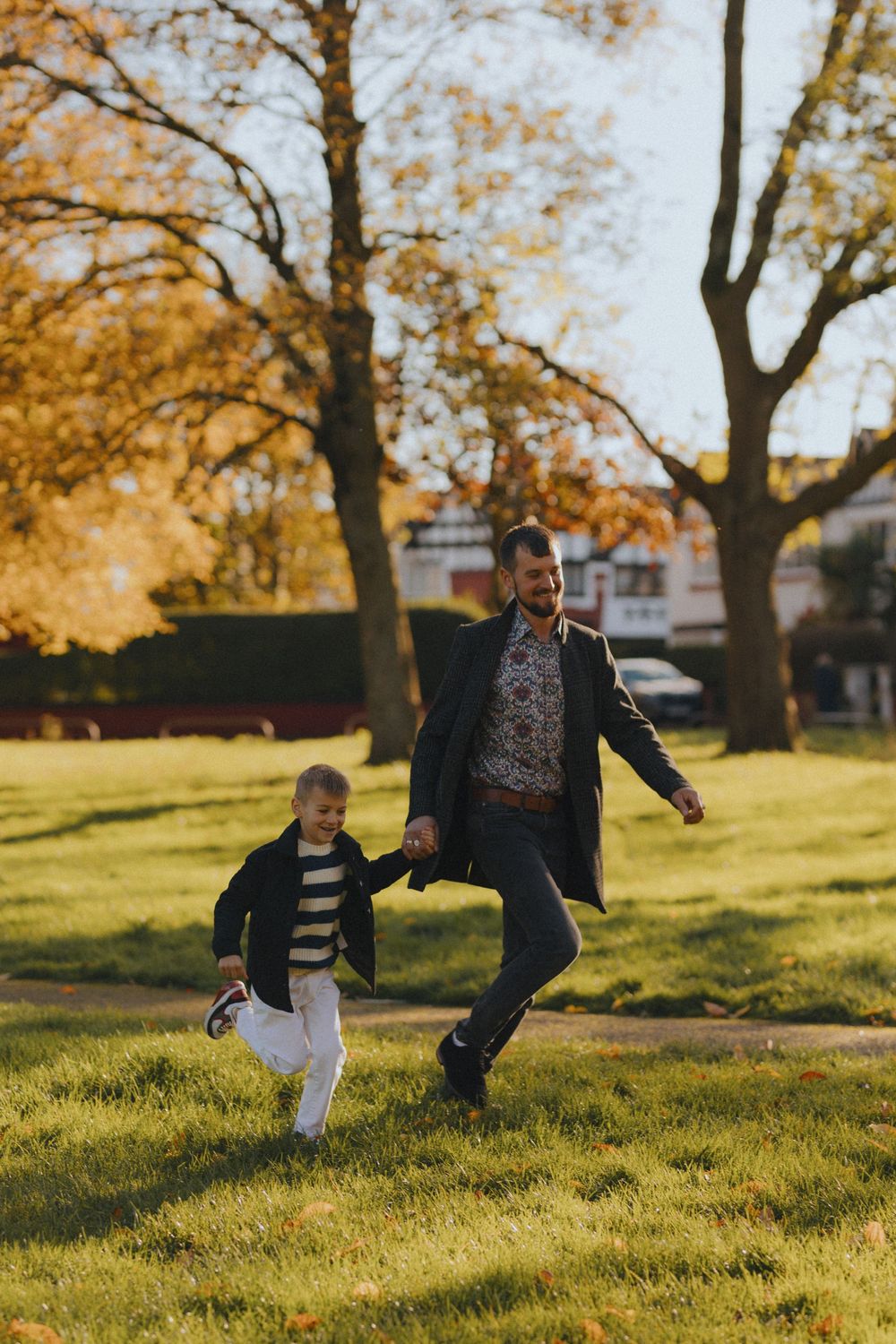 Family playing together in a grassy park during golden autumn afternoon light.