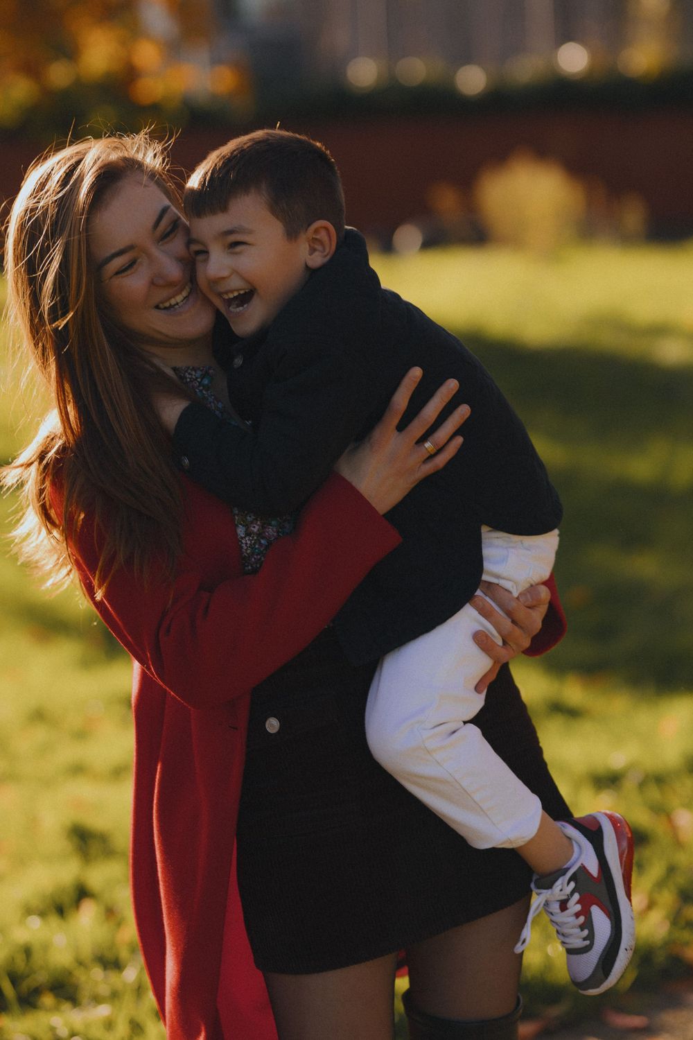 Parent and child sharing joyful moments while playing outdoors in warm sunlight.