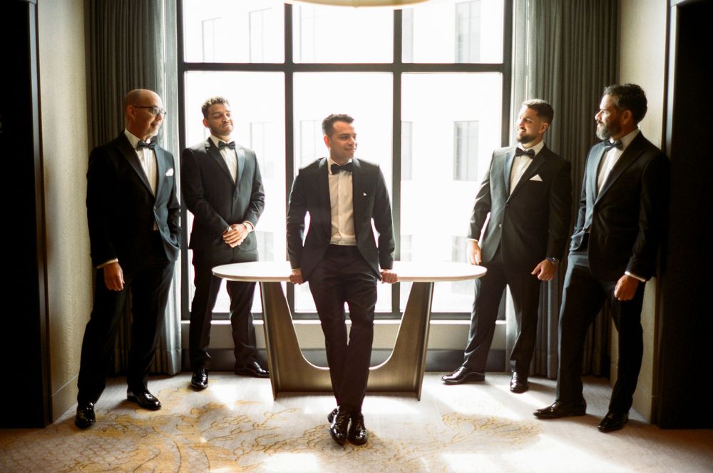 Silhouetted figures stand in front of bright windows in a formal gathering space.