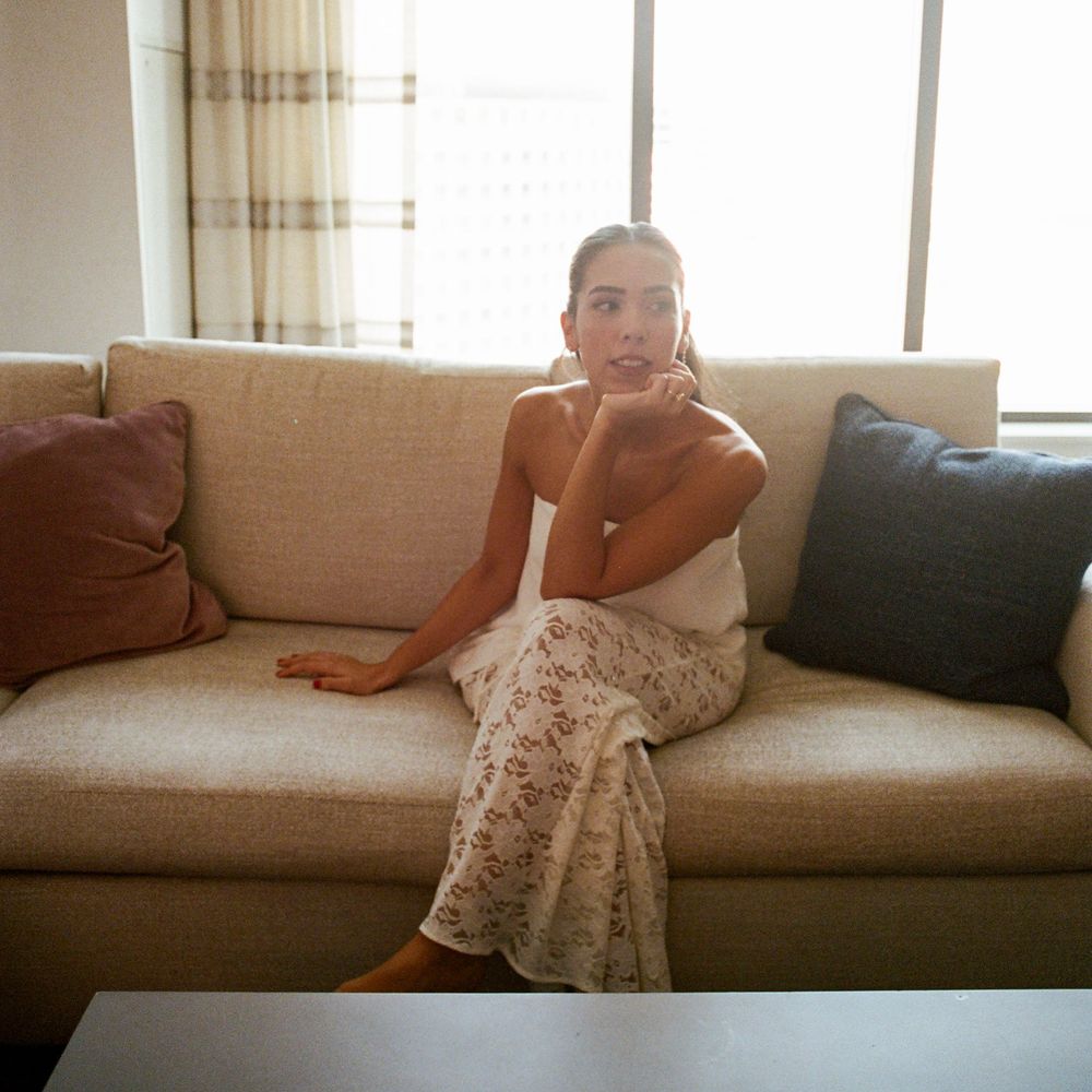 Person lounging comfortably on a beige couch with decorative pillows in a sunlit living room.