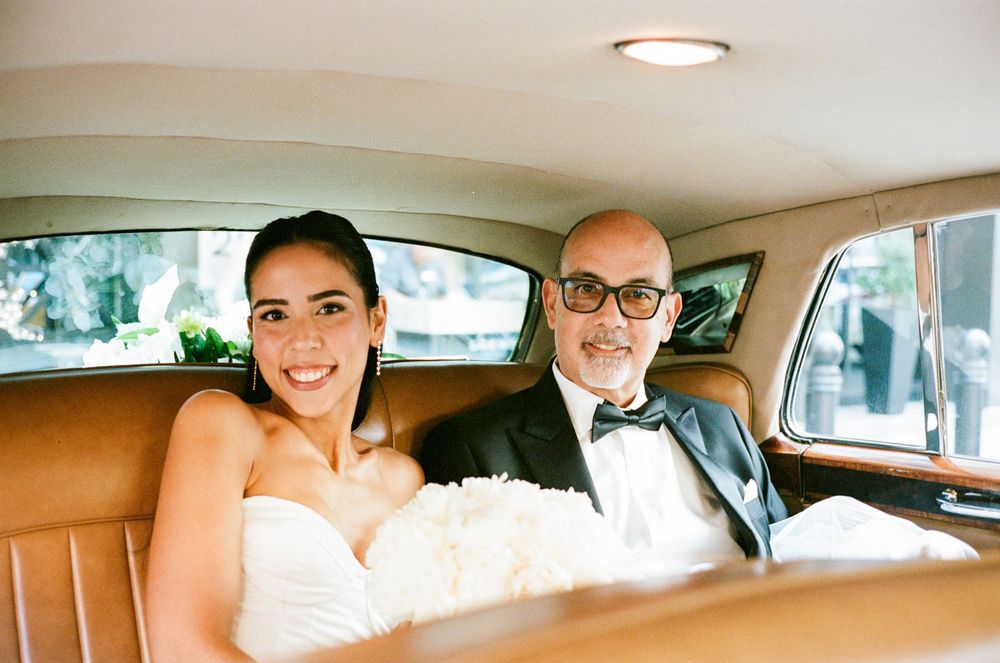 Wedding couple shares intimate moments in the back seat of a vintage car during their special day celebration.