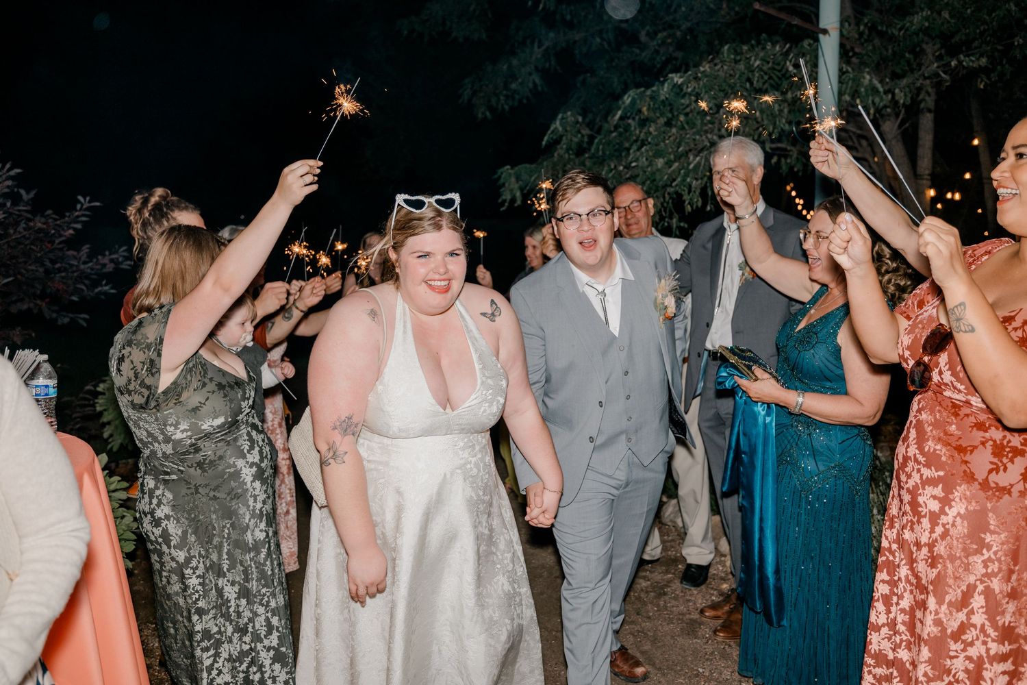 Wedding celebration with guests dancing and celebrating at an outdoor evening reception.