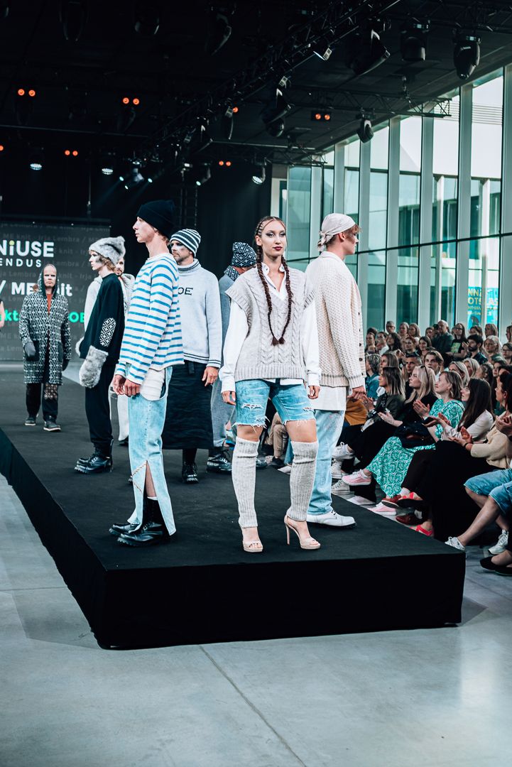 Models walk the runway in nautical-inspired white and blue striped outfits during a fashion show presentation.