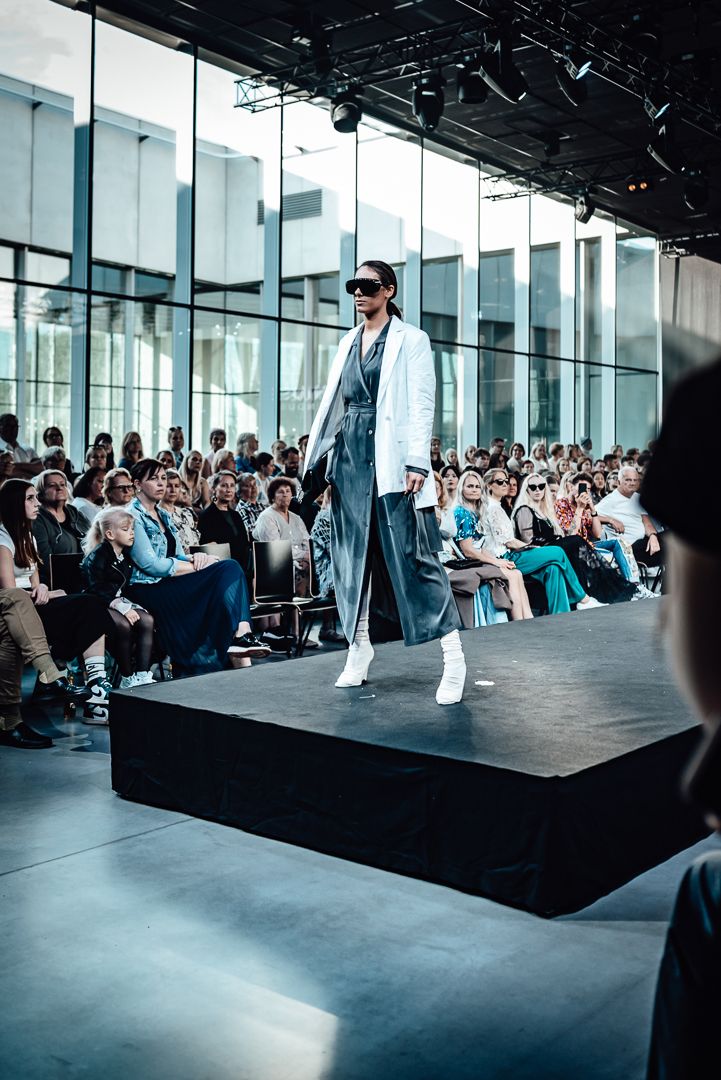 Business audience watches attentively during a corporate presentation in a modern glass-walled conference space.
