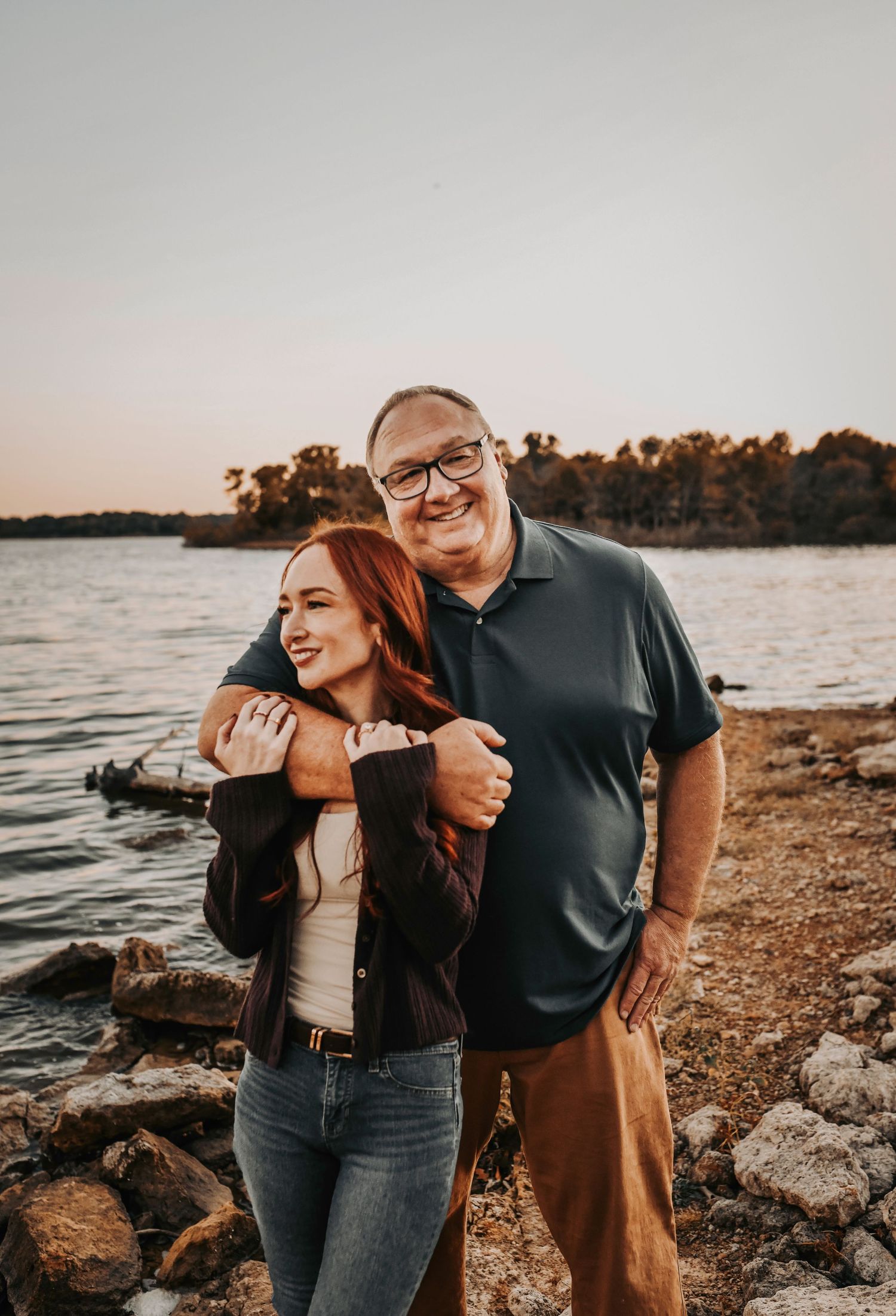 sweet moment between father and his adult daughter cuddling next to the lake