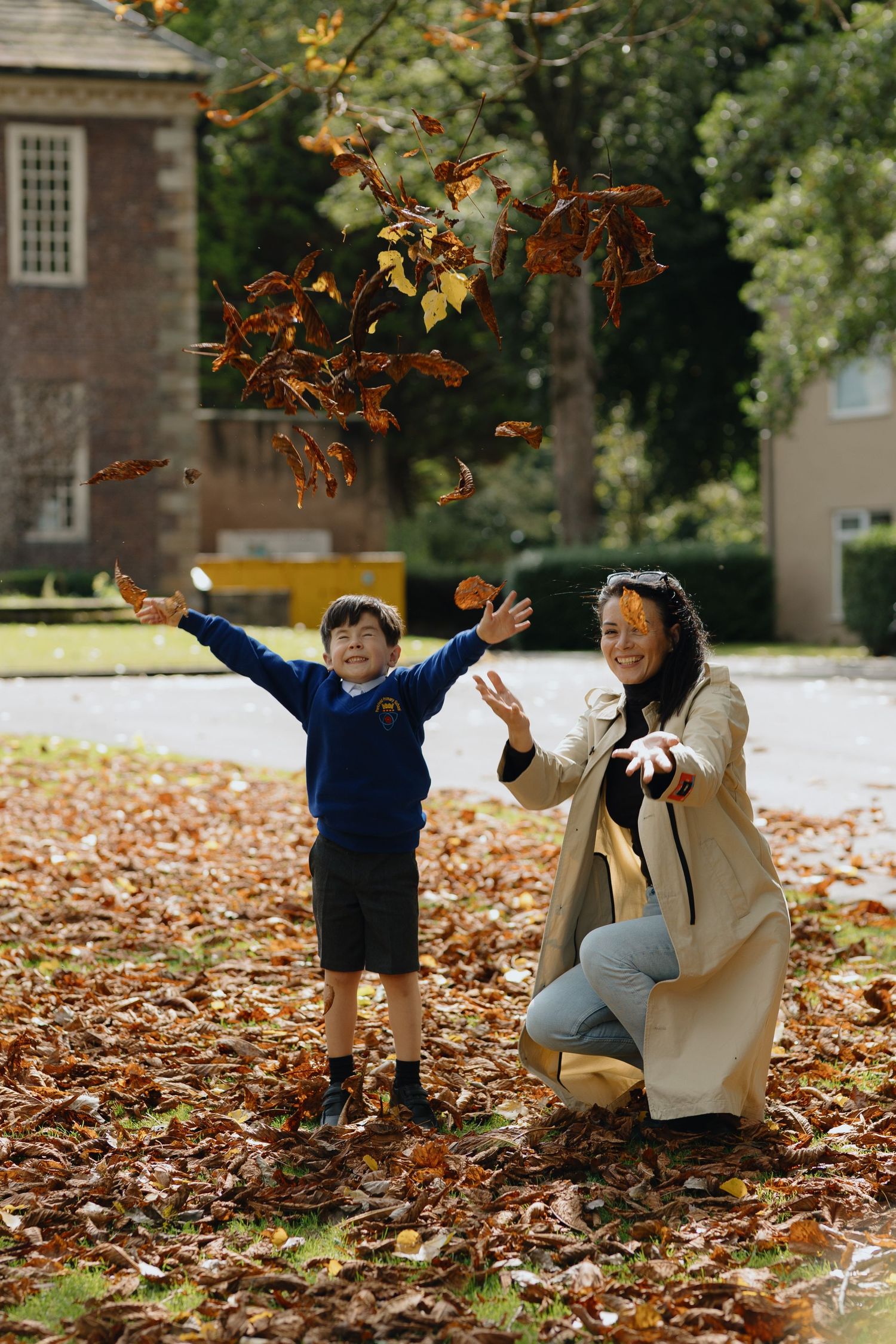 A series of candid outdoor portraits showing warm embraces between two people on autumn ground with fallen leaves.