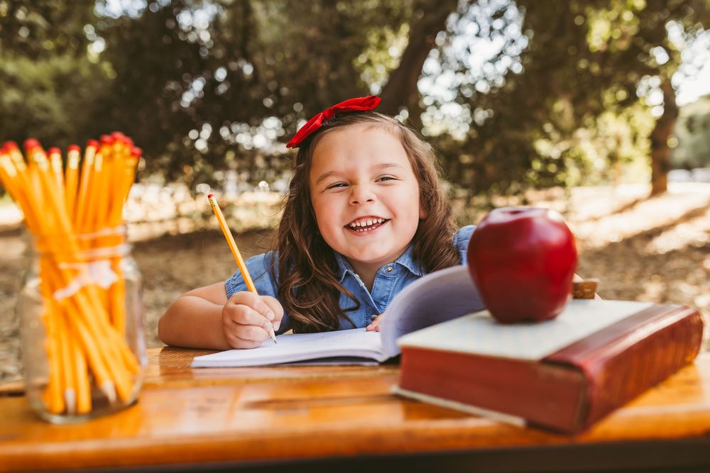 Nostalgic back-to-school scene with wooden desk, school supplies and sunlit forest backdrop.