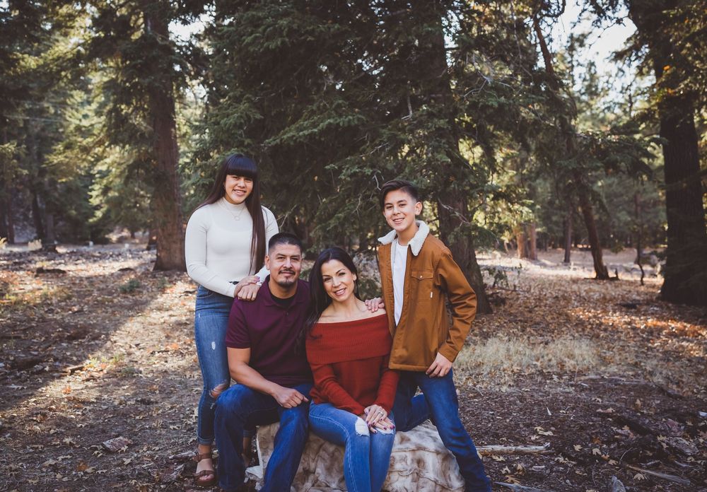 A group poses together on autumn forest ground surrounded by tall evergreen trees in the san bernardino mountains