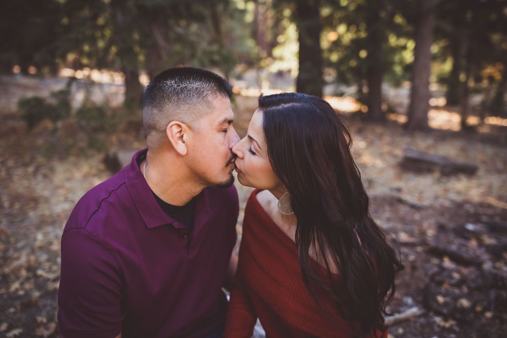 Romantic encounter between couple in casual attire amid pine trees during golden hour.