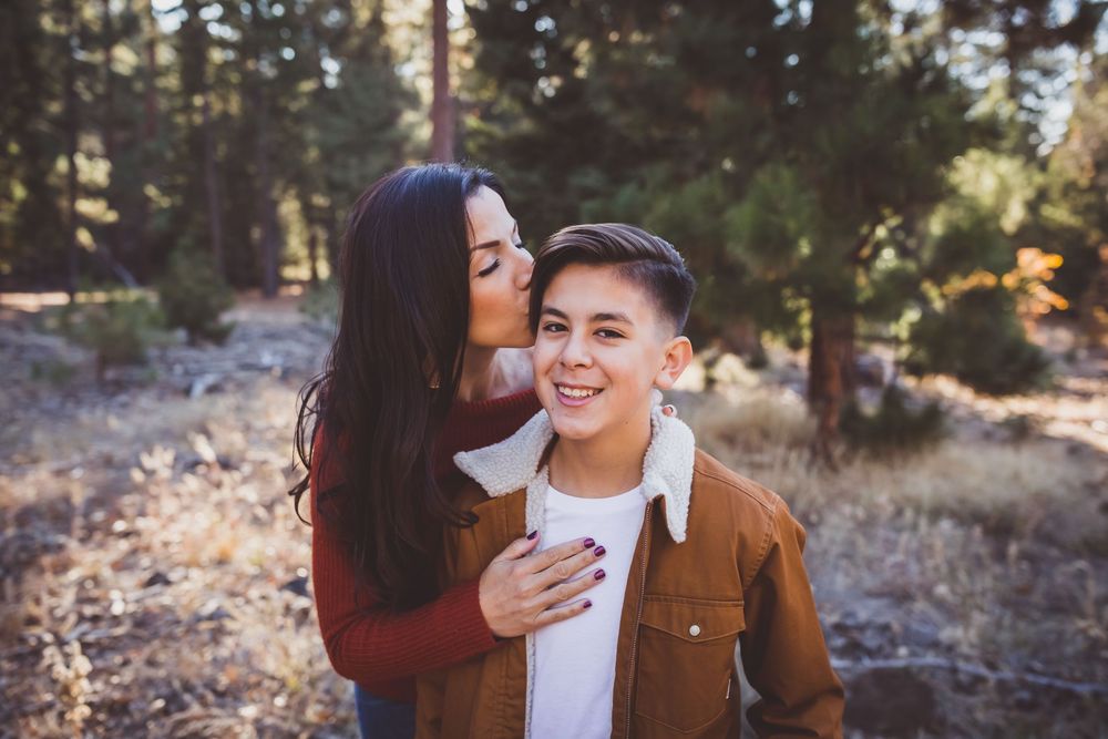 A couple stands close together in sunny forest scenery during a romantic outdoor photo session.