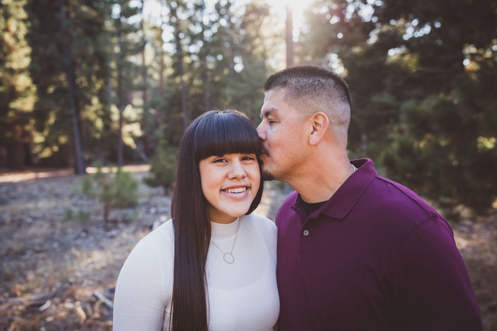 Intimate portrait session featuring joyful expressions against a forested backdrop.