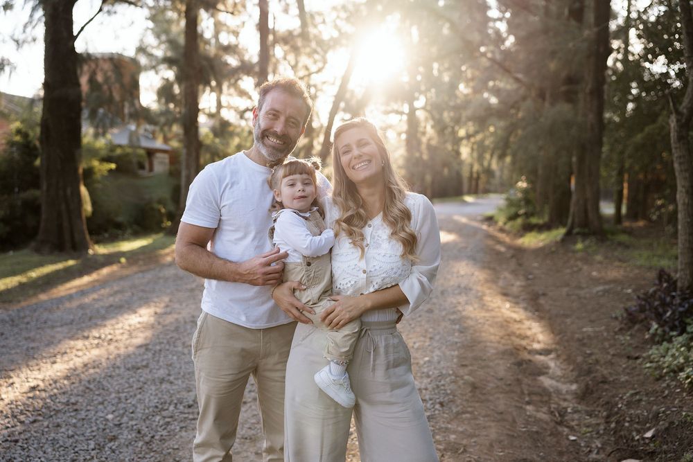 A family enjoys tender moments together on a sunlit gravel path at golden hour, creating a warmth-filled outdoor scene.