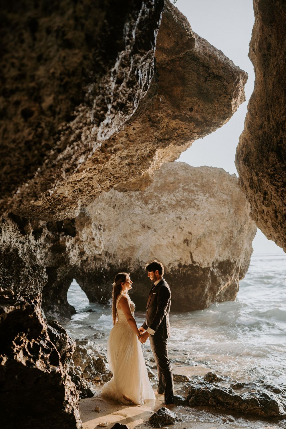 Intimate wedding portraits inside a natural beach cave with ocean views.
