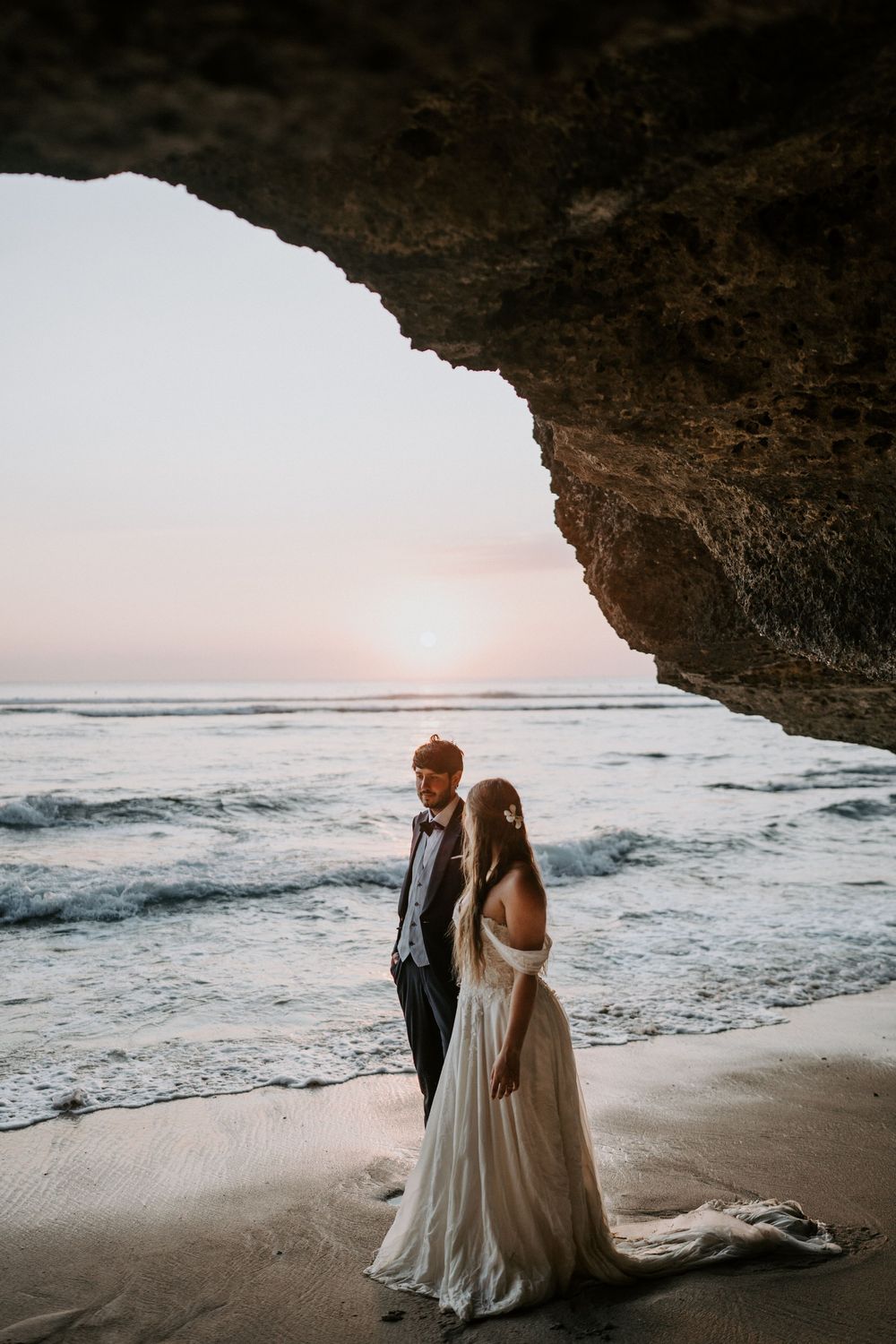 Dreamy beach wedding photography featuring a couple silhouetted against ocean waves.