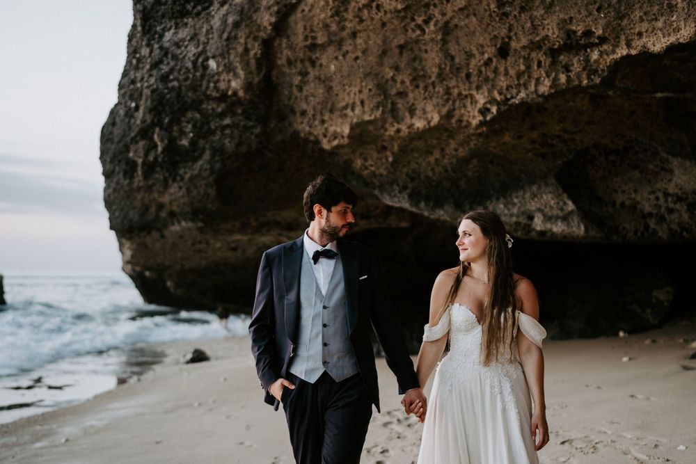 Scenic beach wedding portraits captured against dramatic coastal rock formations.