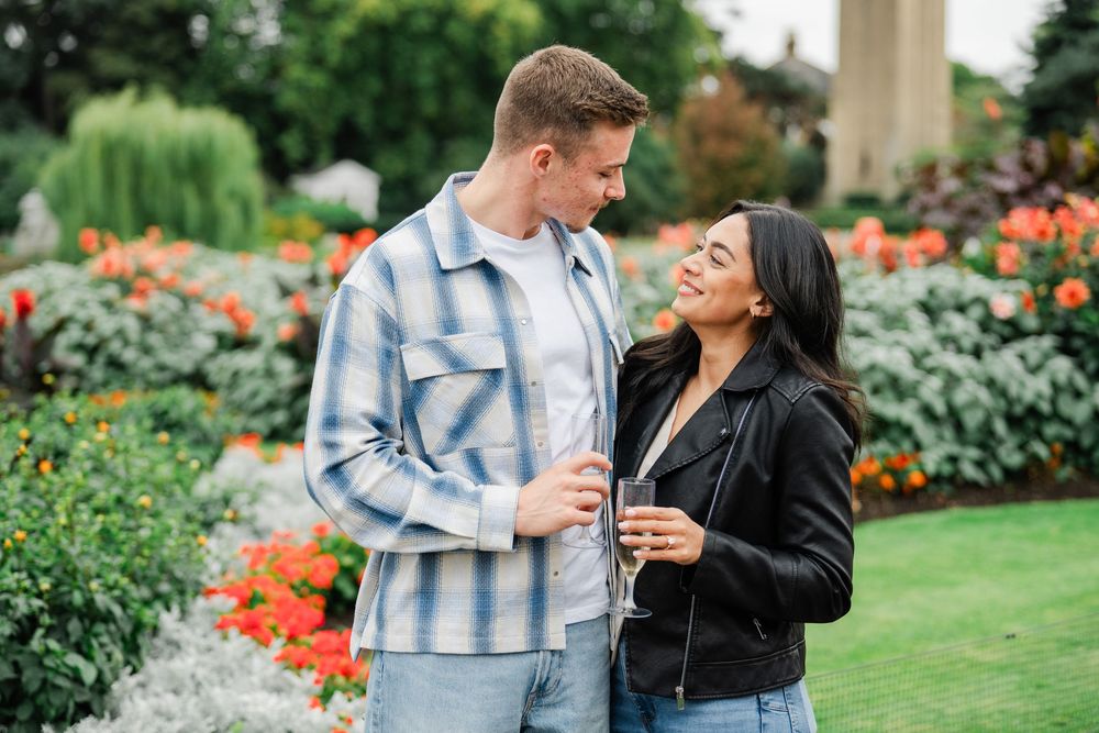 A couple shares a romantic moment while standing in a blooming garden with colorful flowers and lush greenery.