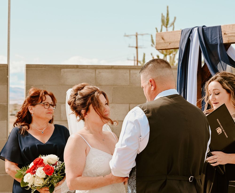 A wedding couple shares an intimate kiss as bridesmaids and other wedding party members look on in mixed reactions.