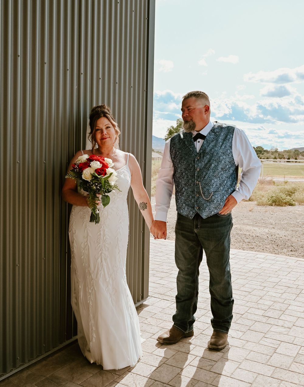 A couple in elegant wedding attire share an intimate moment together on a beautiful desert landscape backdrop.