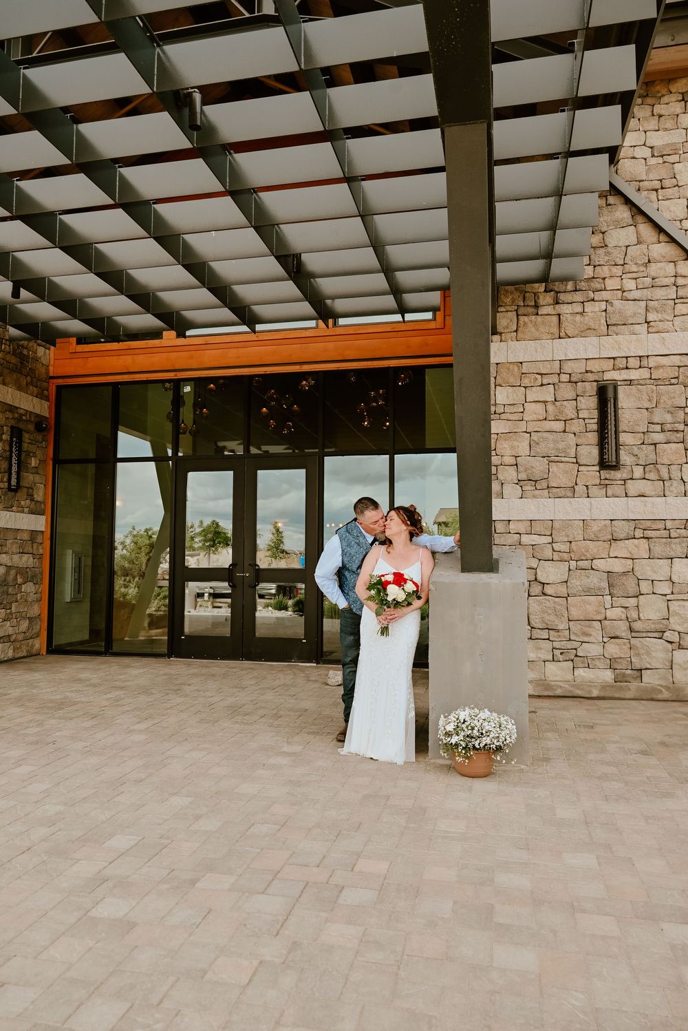 Wedding ceremony in an elegant stone pavilion with exposed wooden beams and natural lighting.