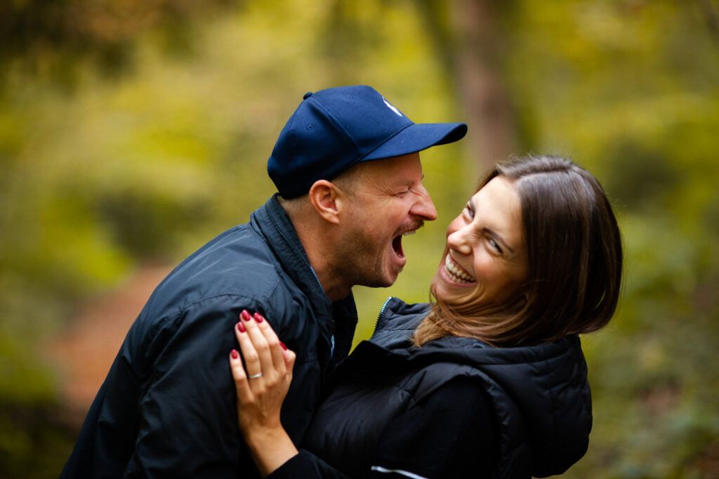 A couple shares a joyous laugh together during an outdoor autumn photo session.