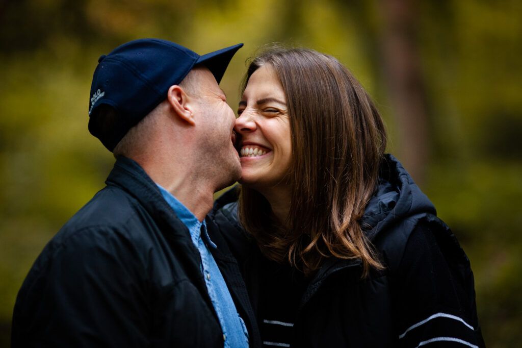 Happy couple embraces together outdoors in a warm fall setting with natural bokeh background.