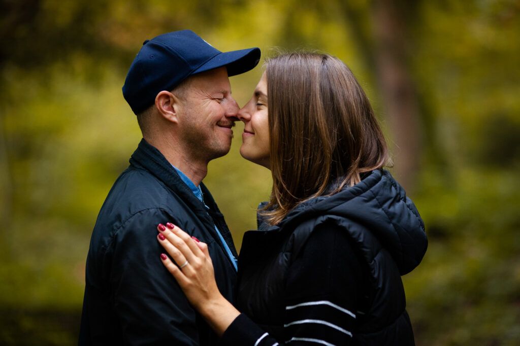A happy couple sharing an intimate moment outdoors with autumn foliage in the background.