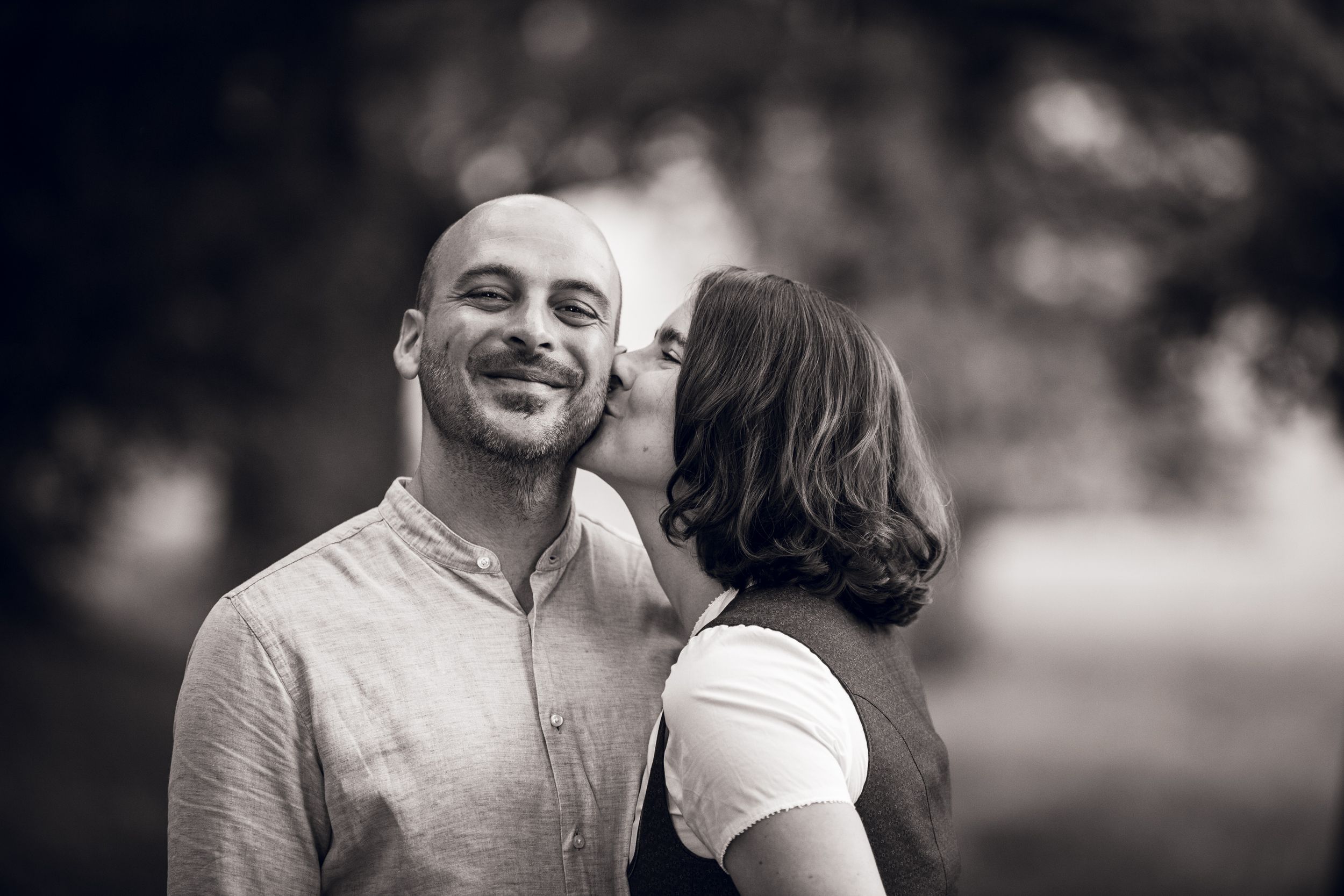 A couple shares intimate moments outdoors in a series of black and white romantic engagement photos.