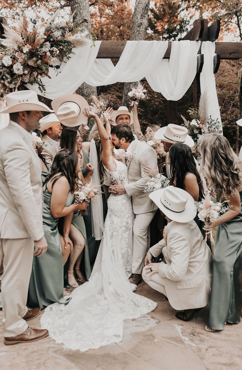 Bride and groom smiling with full wedding party in front of Whispering Oaks barn venue