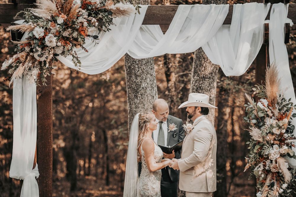 Bride and groom exchanging vows under the altar framed with greenery and floating candles