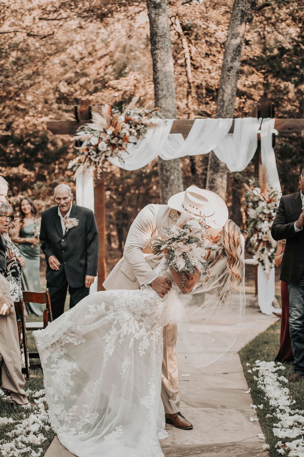 Rustic barn wedding ceremony with romantic greenery and flowing white fabric