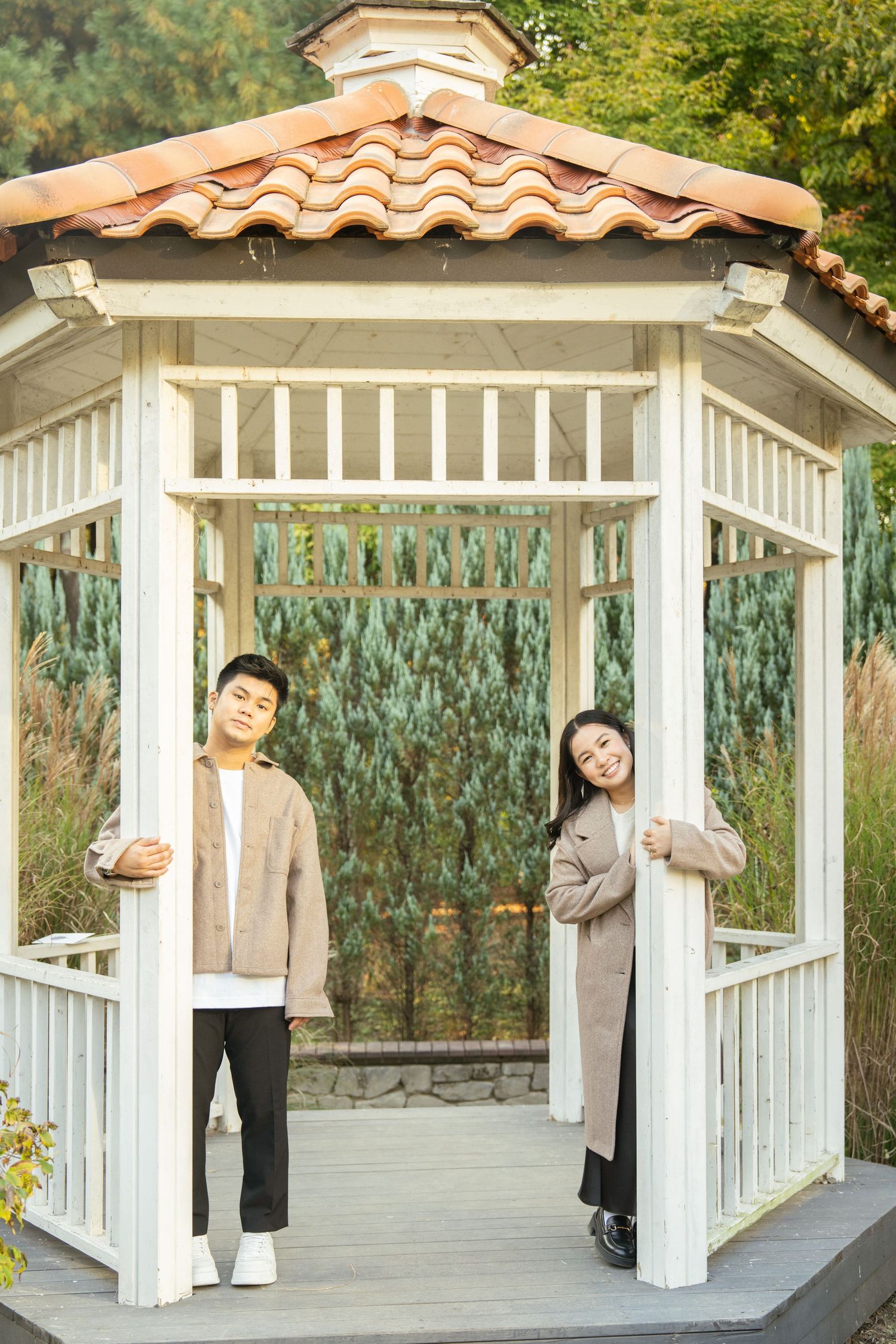 A sequence of playful poses taken in a white garden gazebo with terracotta roof tiles and natural landscaping.