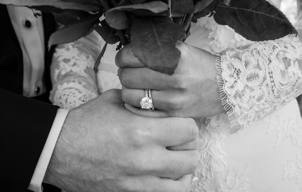 A detailed close-up sequence showing engagement ring placement on a woman's finger wearing a white lace dress.