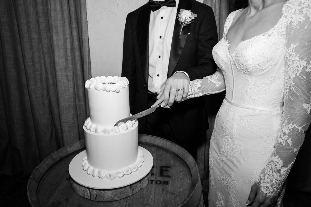 Wedding couple cuts their elegant white wedding cake at the reception in formal attire.