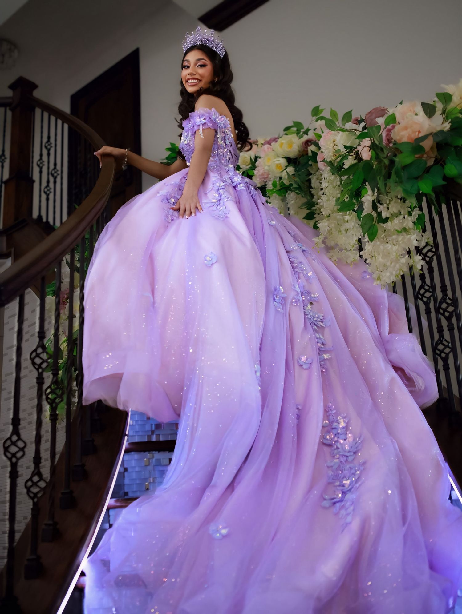Dramatic lavender ballgown with glittering butterfly details and flowing tulle fabric cascades down an elegant staircase.