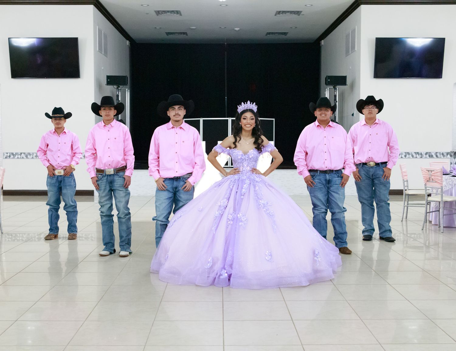 Six western dancers in cowboy hats and pink shirts waiting in line during a performance rehearsal.