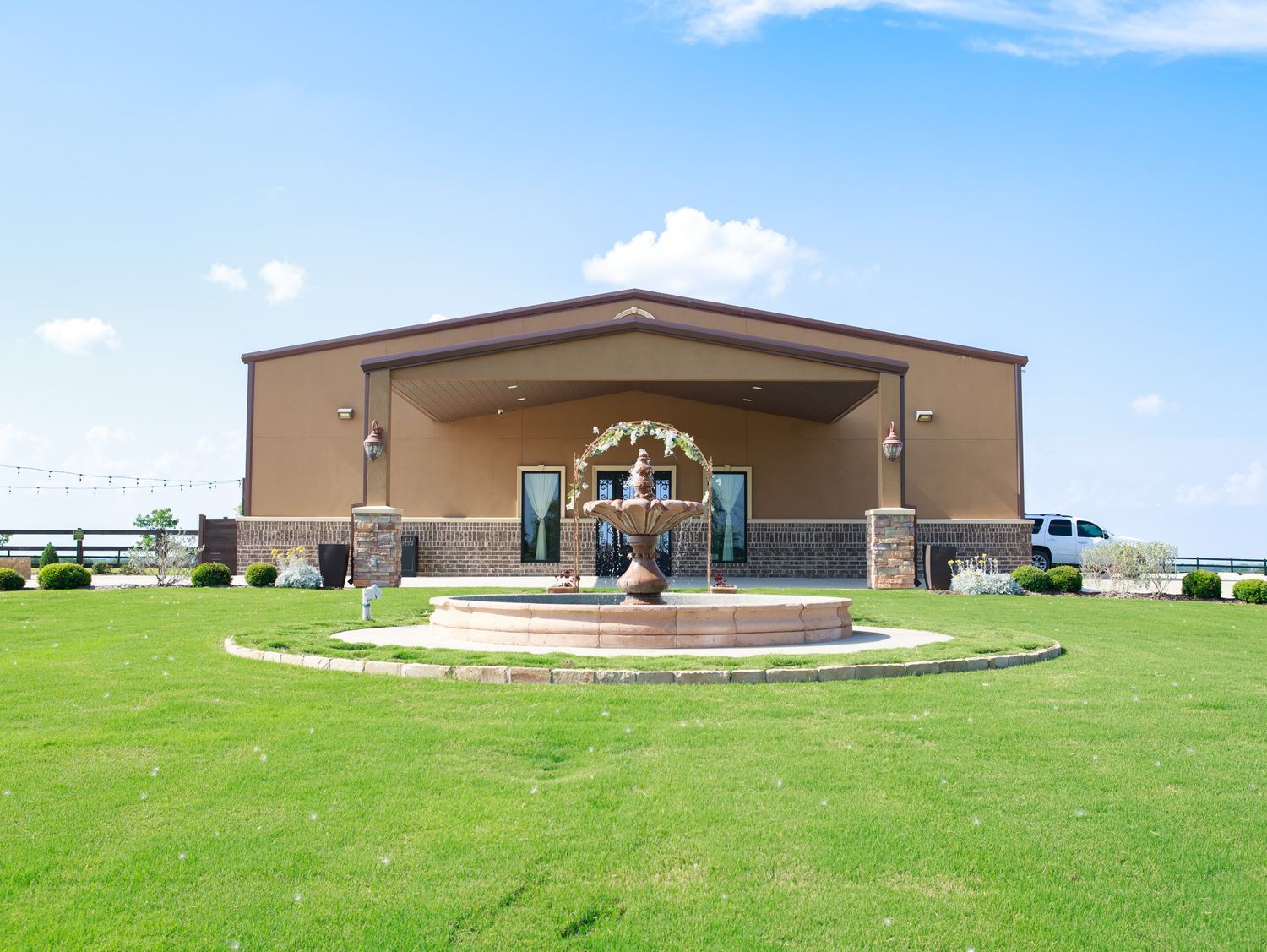 A panoramic series of photos showing a brown commercial building and amphitheater on a grassy hillside under blue skies.