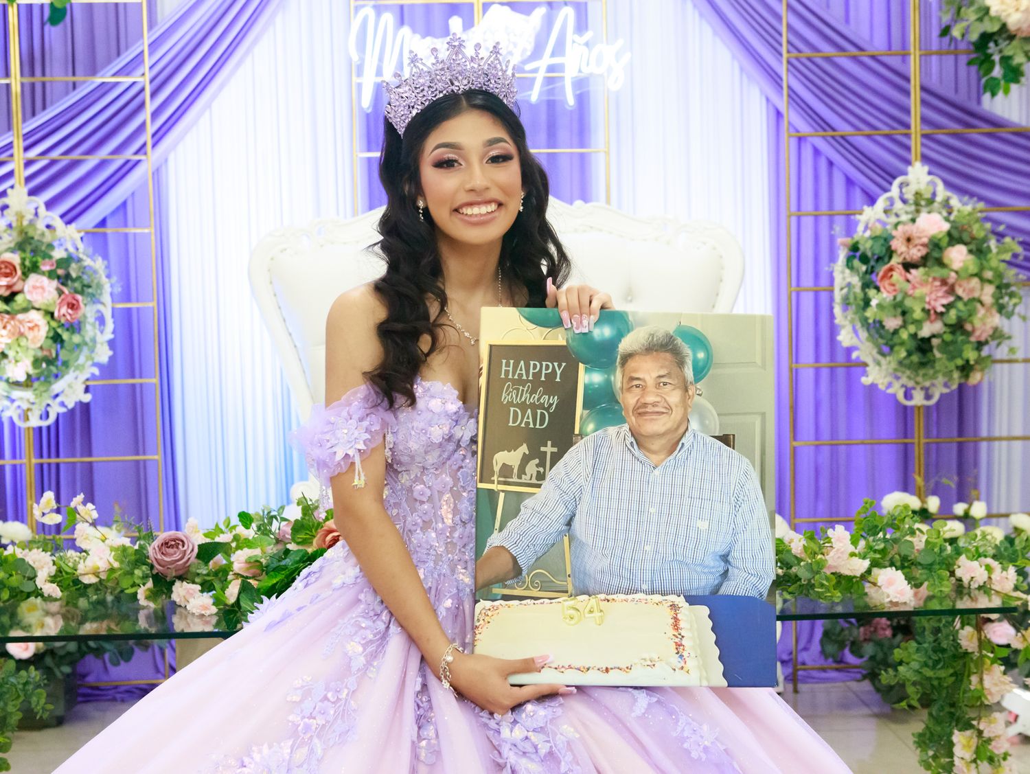 Elegant purple and white quinceanera celebration setup with floral arrangements and draped fabric decor.