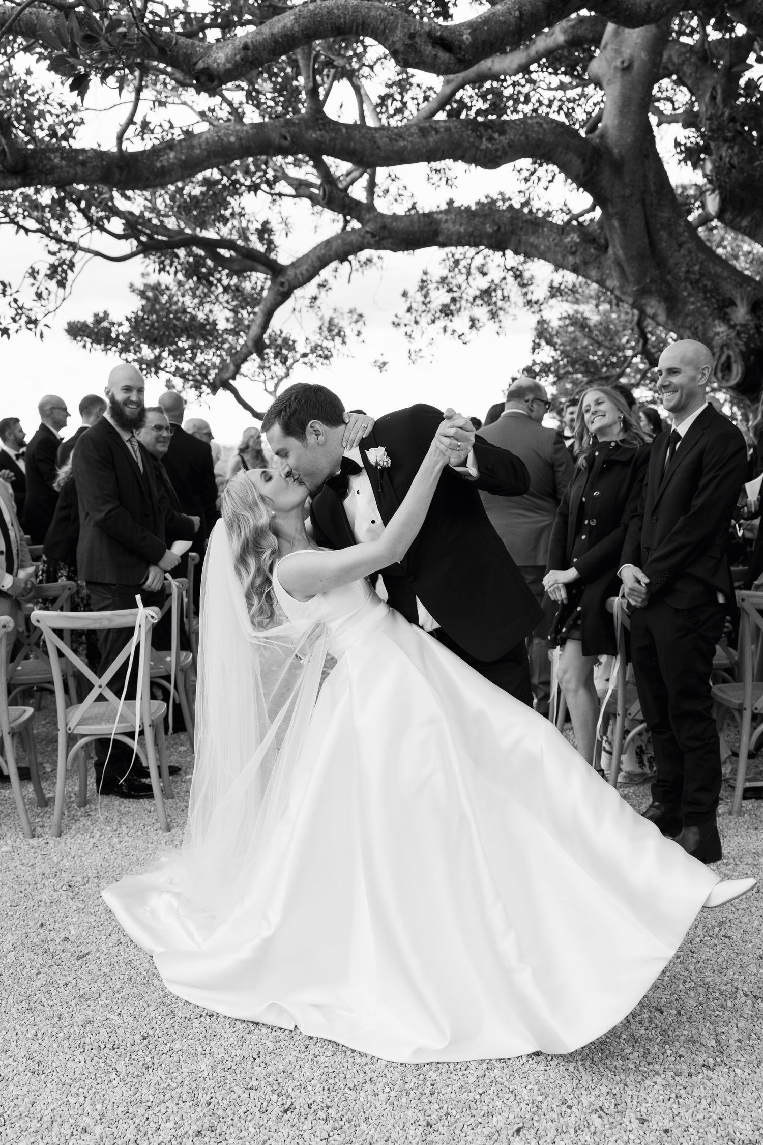A sequence of dance moves at an outdoor wedding celebration under a large tree with guests looking on.